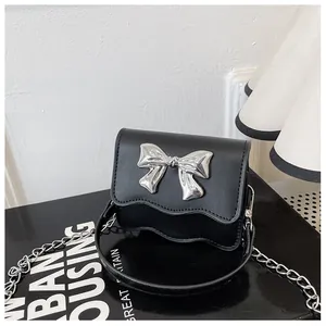 Detailed close-up of a black PU leather bag with a silver bow and stylish chain strap