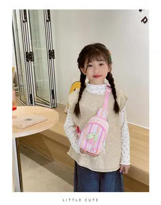 Close-up of pink striped kids crossbody bag with green cherry pendant accessory