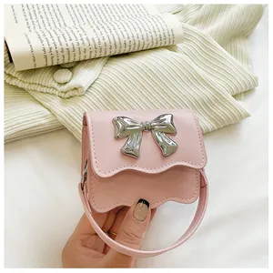 Close-up of pink mini handbag featuring a large silver bow and scalloped edge detail