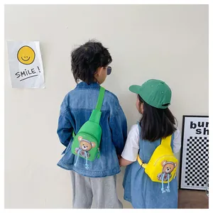 Detail view of children's canvas chest bags with cartoon bear prints in yellow and green