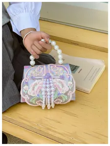 Detail of floral embroidery, traditional silk knot, and pearl handle on a purple bag