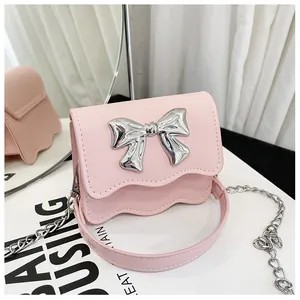 Detail of pink PU leather mini bag with a metallic bow and elegant scalloped edge