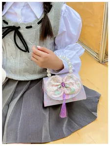 Detailed close-up of a purple pearl handle bag featuring lace embroidery and long tassels