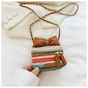 Detail of colorful woven mini bag featuring a brown leather bow and golden chain strap