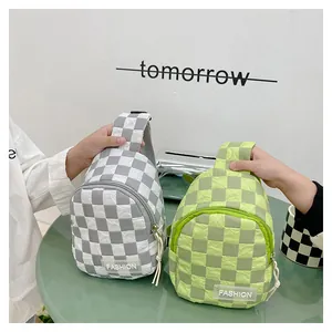 Detail view of stylish checkered nylon chest bags in gray and green on a green table