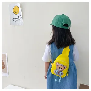 Rear view of a yellow cartoon bear crossbody bag worn by a child in an outdoor setting