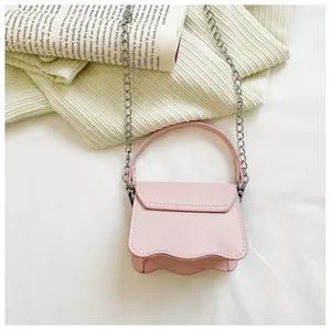 Detail of light pink PU mini bag featuring wavy edge design and silver chain strap