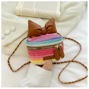 Detail of mini rainbow woven bag featuring a large leather bow and metal chain strap
