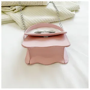 Detail of pink PU leather mini bag featuring silver bow decor and wavy bottom edge