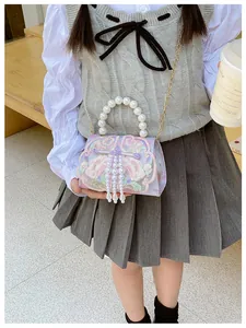 Detail of girl's embroidered floral handbag featuring pearl tassel and gold chain strap