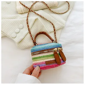 Detail of colorful woven straw mini crossbody bag with leather handles and chain strap