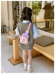 Toddler girl wearing pink striped chest bag with 3D flower detail in a cafe setting