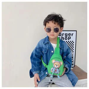 Green kids crossbody bag featuring a cartoon bear print worn by a young boy outdoors