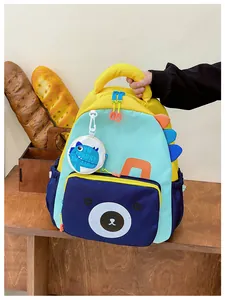 Detail of colorful children dinosaur backpack showing side fins and a small bear front pocket