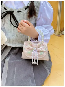 Close-up of pink embroidered bow, green leaves, and pearl fringe on a kid's handbag