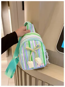 Detail of green striped kids bag featuring yellow bow and floral charm decorations