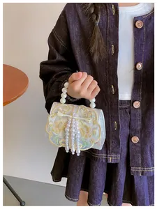 Detail of vintage embroidery girl shoulder bag with pearl tassel and golden floral pattern