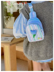 Detail of striped crossbody bag with 3D blue flower and adjustable canvas strap