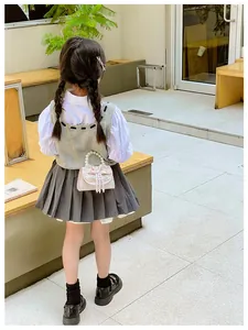 Girl wearing pink mini bag with pearl handle and bow, styled with knit vest and skirt