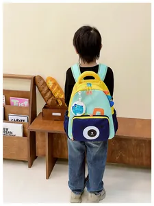 Detail view of a yellow kids backpack with bear print and dinosaur fins on wood background