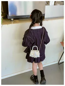 Detailed back view of girls traditional embroidery bag with pearl handle and tassel on model