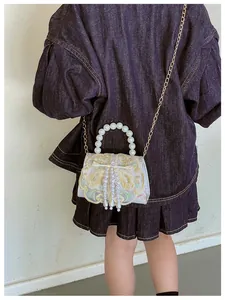Detail of Chinese style embroidery on mini bag with pearl handle and golden chain strap