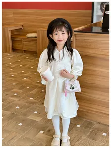 Gros plan sur une robe blanche en jacquard avec boutons chinois et sac panda rose