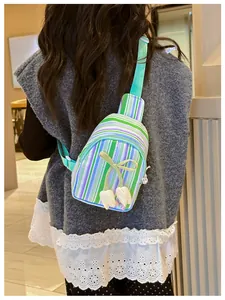 Close-up of girls striped crossbody chest bag with floral charms and green ribbon knot