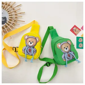 Detail view of colorful cartoon bear nylon sling bags in yellow and green for kids