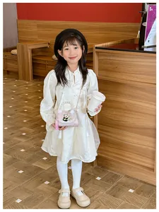 Détail du sac panda rose avec poignée en perles et pompons sur une robe pour enfants