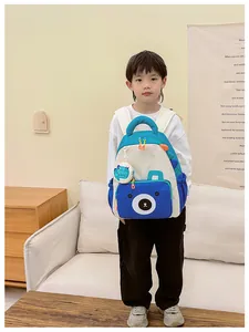 Blue and cream kids backpack with cute bear pocket and cartoon charm shown in a home setting