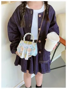 Close-up of children's blue crossbody bag with pearl handle and traditional embroidery
