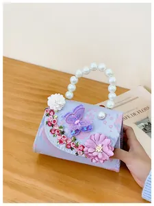 Détail du sac brodé violet avec motifs floraux, papillon 3D et poignée en perles