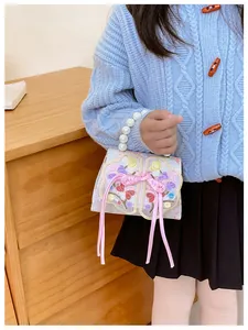 Detail of child handbag featuring floral embroidery, bow tie, and pearl handle beads
