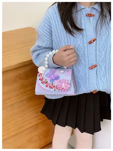 Détail du sac lavande avec papillon 3D, broderies florales et poignée en perles