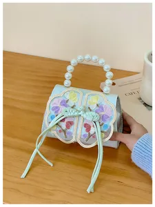 Detail of light blue girls' handbag with pearl handle, floral embroidery and silk ribbons