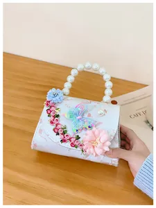Détail de broderie florale et papillon à paillettes sur mini sac blanc à perles