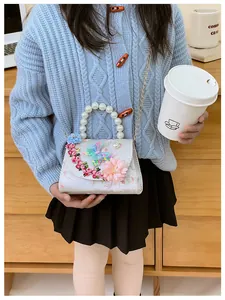 Détail du sac enfant avec poignée en perles, fleur en velours rose et broderie papillon