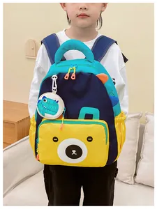 Detail of kids dinosaur backpack with yellow bear pocket and cute round coin purse charm