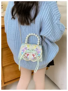 Detailed view of kids' crossbody bag with pearl handle and embroidered butterfly motif