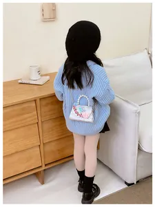 Détail de fleurs et papillons brodés sur un sac à bandoulière blanc nacré pour enfants