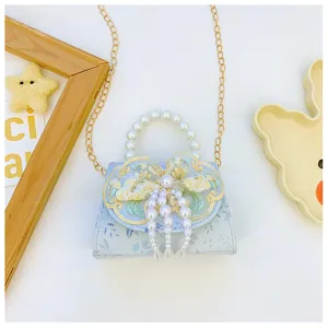 Close-up of floral child bag with pearl handle, lace bow, and tassel details