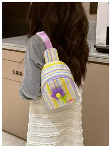 Detail of a kids striped crossbody bag featuring a 3D colorful sunflower and beaded charms