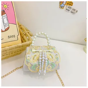 Detailed embroidery on white shoulder bag with pearl handle and tassels