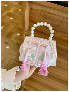 Close-up of pink oriental bow tassel bag with floral embroidery and pearl handle