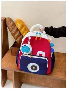 Detail of red and blue kids backpack with cartoon bear print and decorative pendant