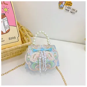 Detail of blue embroidery girl handbag with pearl handle and delicate floral patterns