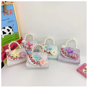 Détail de broderie florale et papillon 3D sur mini sacs macaron avec anse en perles