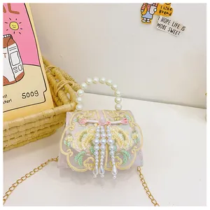 Close-up of pink floral embroidery and pearl tassel detail on children handbag