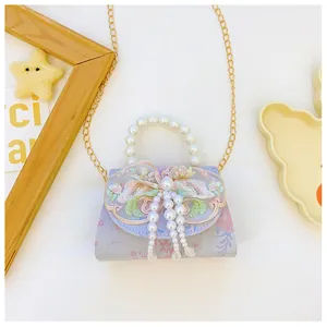 Detail of floral kids handbag featuring pearl handle, lace flower, and beaded tassels